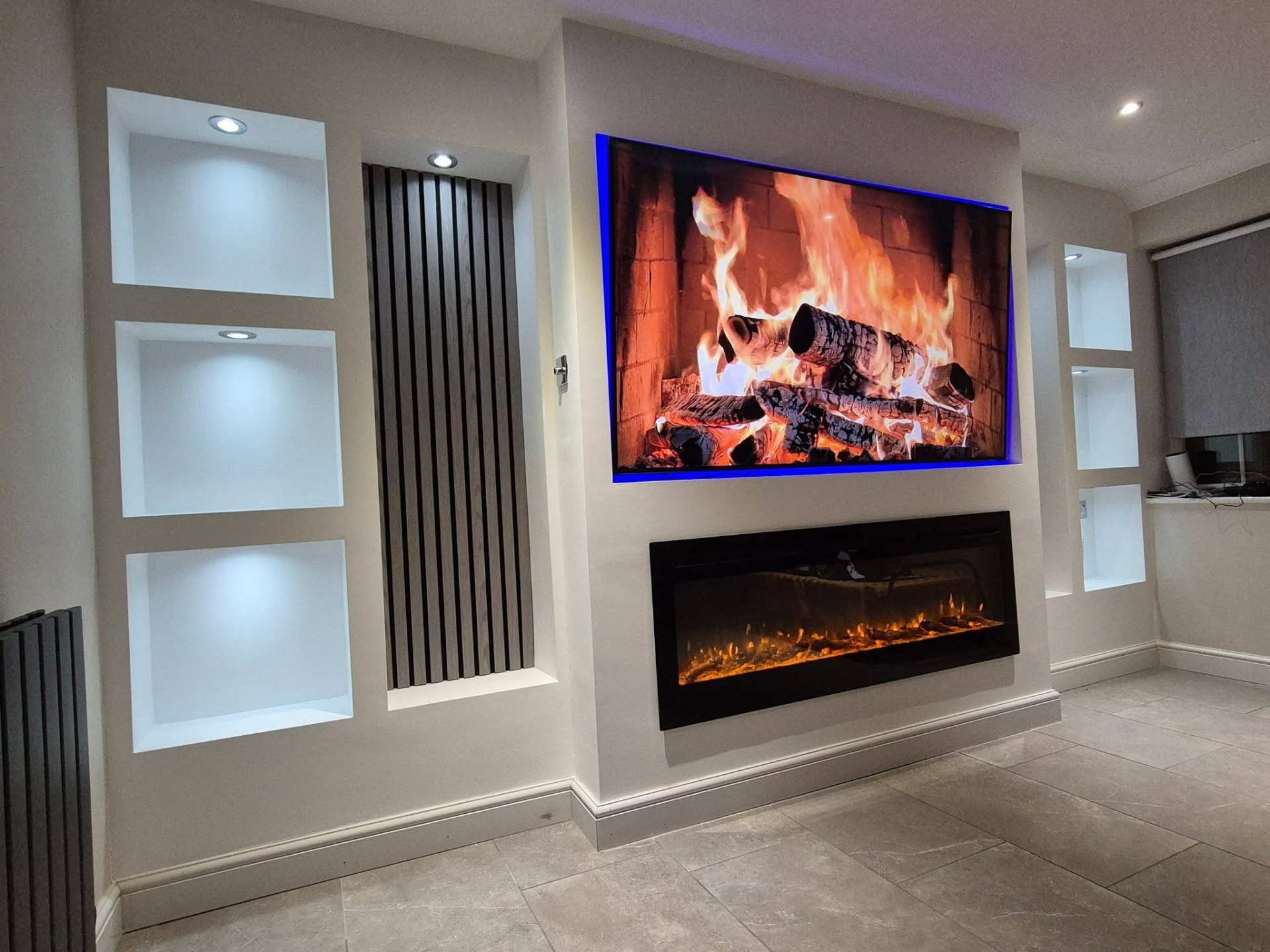 Living room transformed from bare walls into a finished media wall with lit alcoves, inset fire and built-in TV